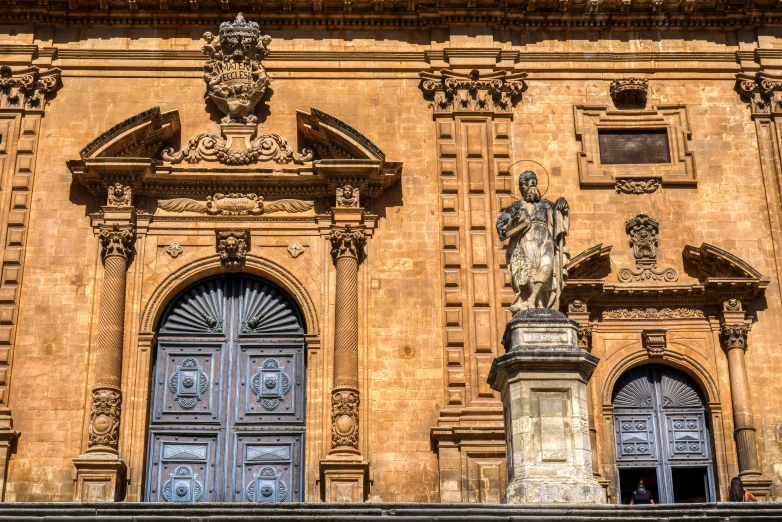 an old building with a statue and two blue doors