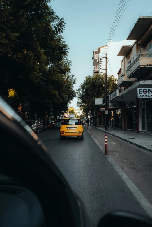 yellow car on street next to row of shops