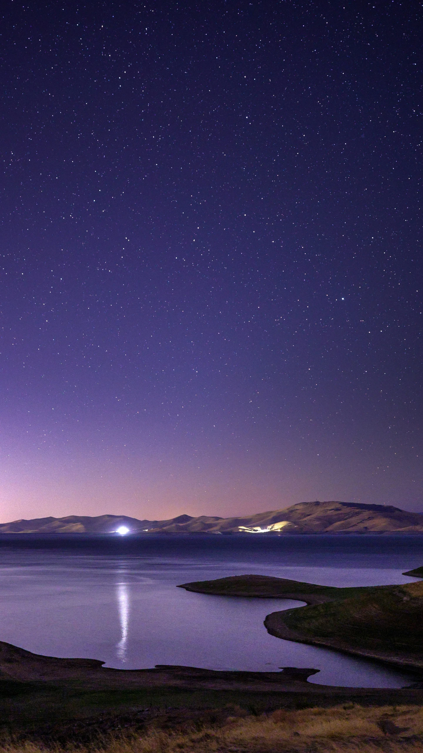 a body of water under a star filled sky