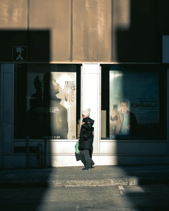 person walking down street in front of store with large window