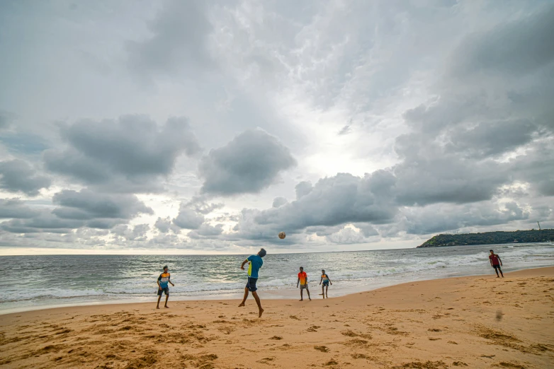 a group of people playing with a kite on a beach