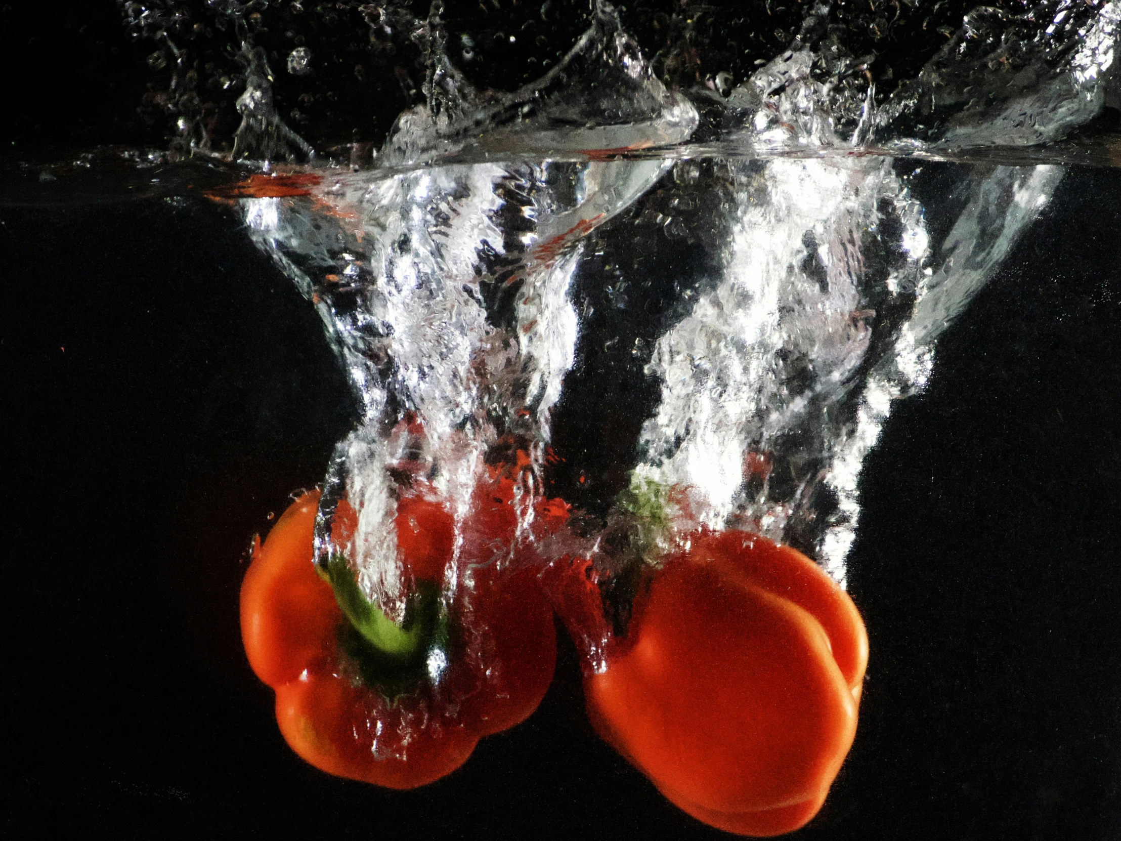 two oranges are in the water with splashes
