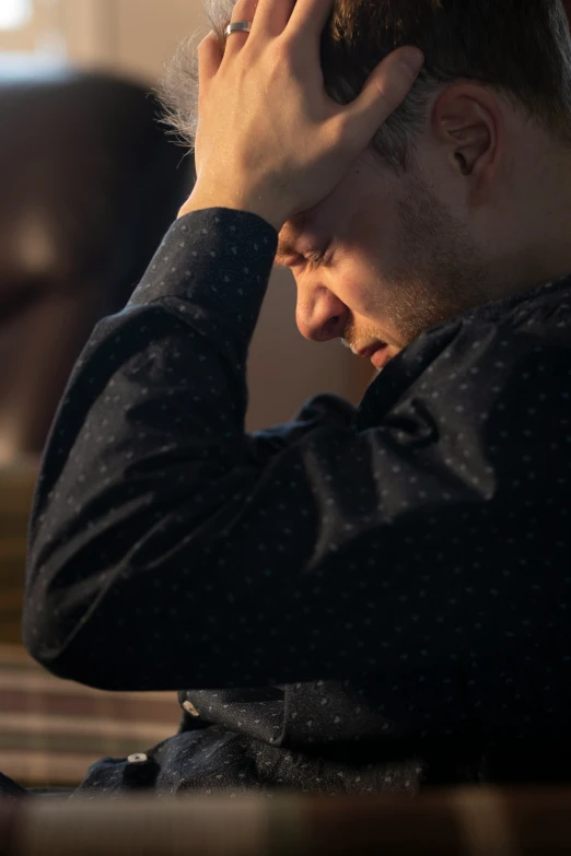 man looking down at his cellphone and holding his hand to his ear