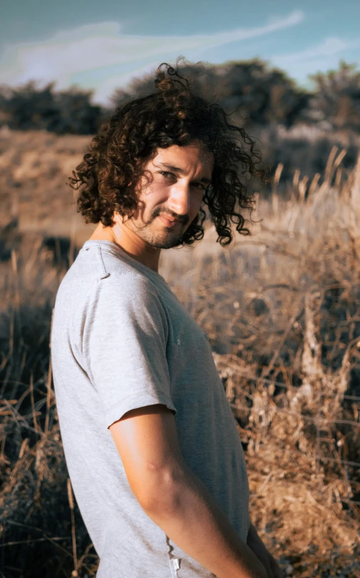 a man standing outside in a field smiling