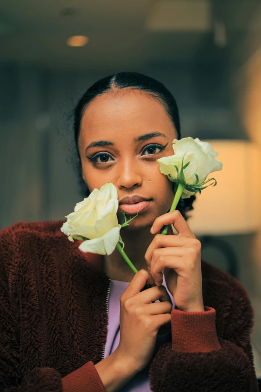 a woman holding two flowers near her face