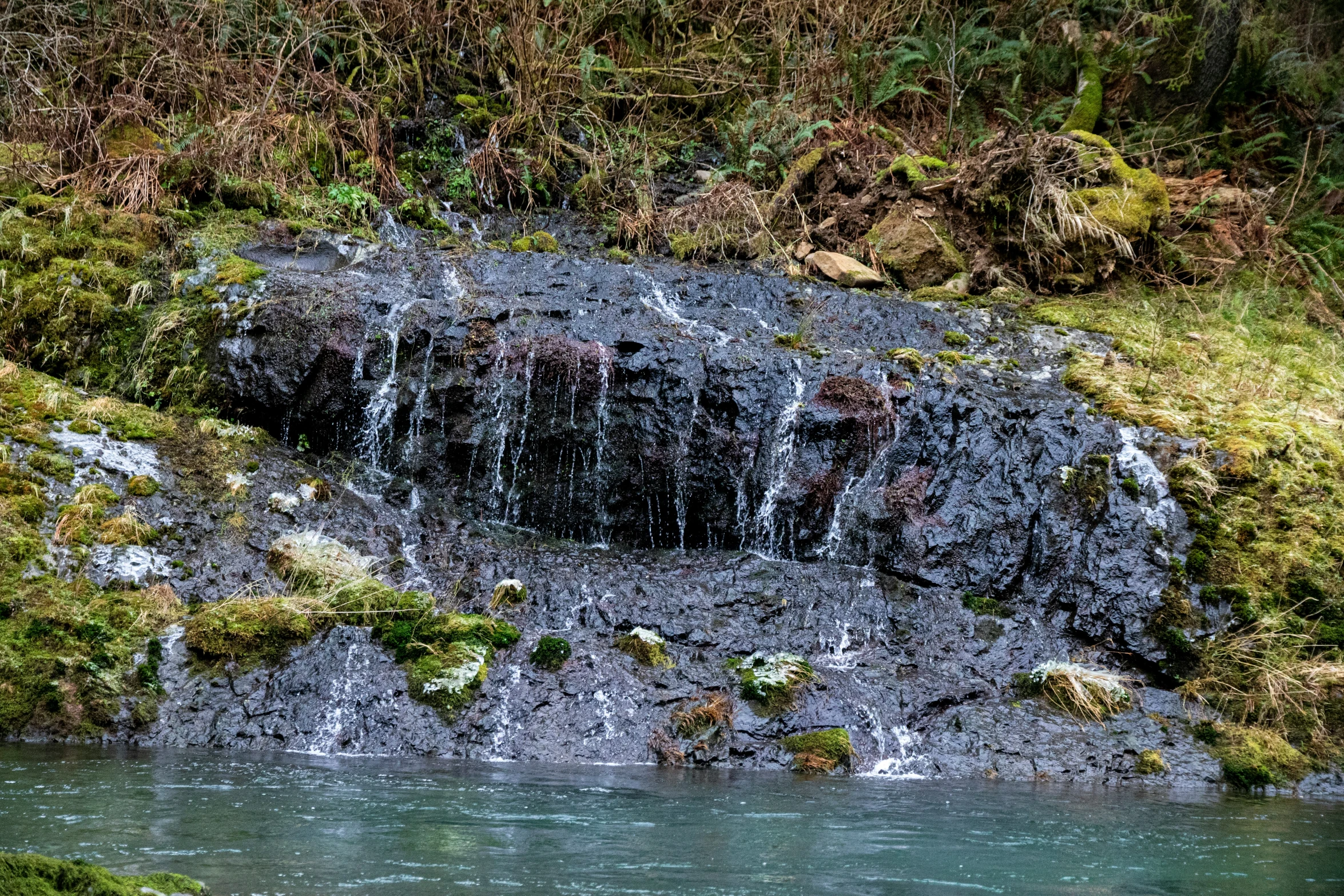 a waterfall running over a small waterfall into the middle of a lake