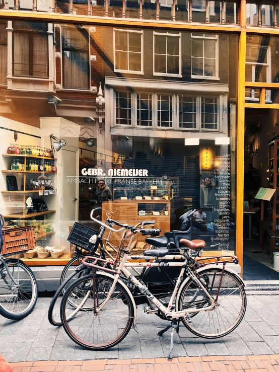 bicycles are parked outside a shop window while people walk past