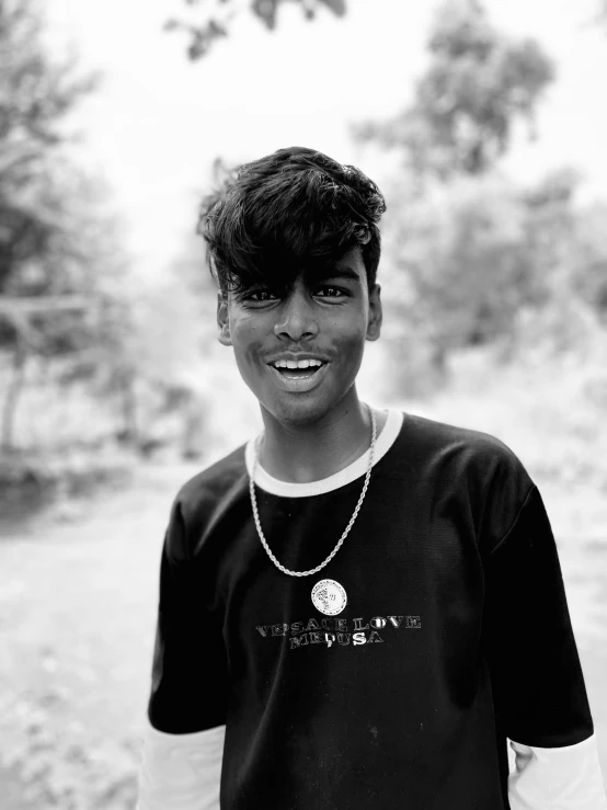 a smiling  in a black shirt and chain