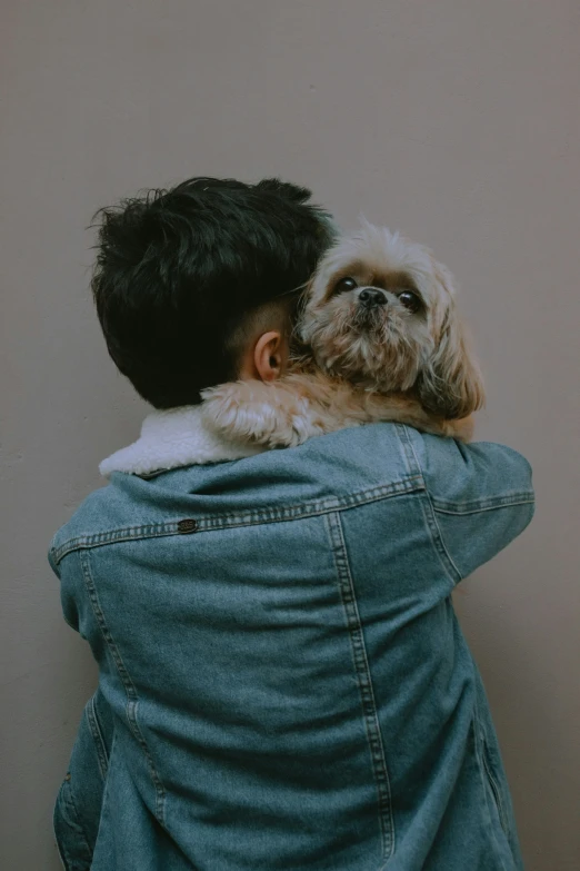 a man is holding his small dog behind his back