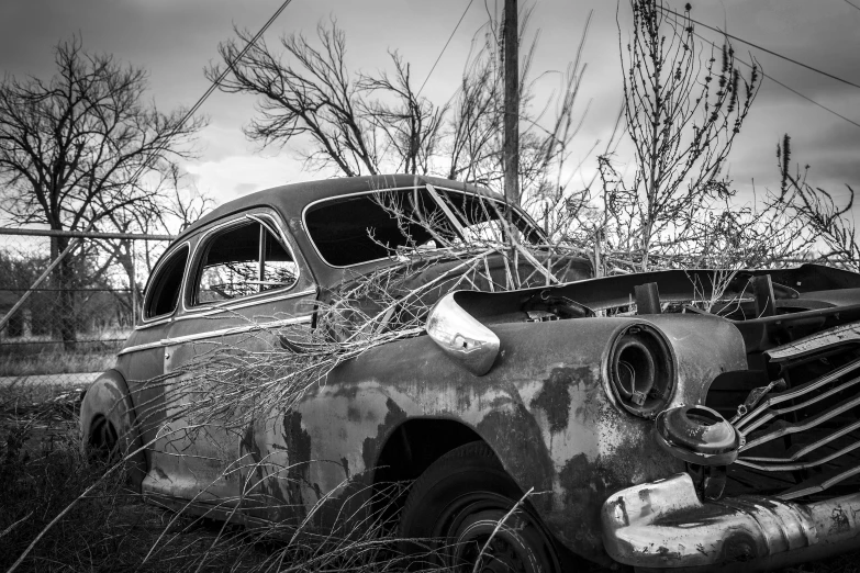 an old broken down car that is abandoned and is sitting in a field