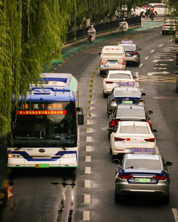 several buses, cars and traffic wait for passengers to board