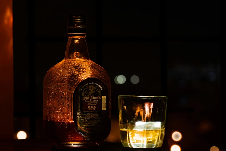 a bottle of liquor next to an ice cube next to a glass