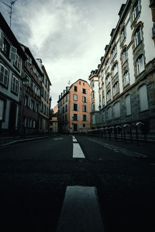 several buildings line the roadway and road with dark clouds overhead