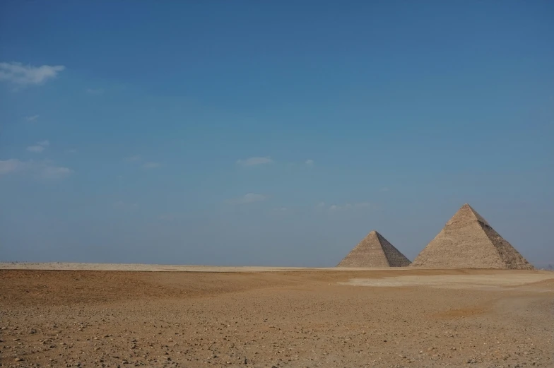 three pyramids sit in the desert under a blue sky