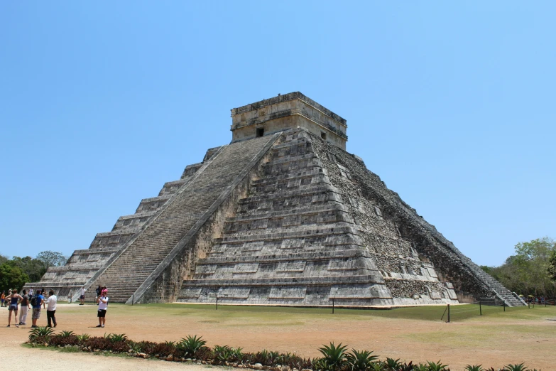 tourists stand in front of an ancient pyramid