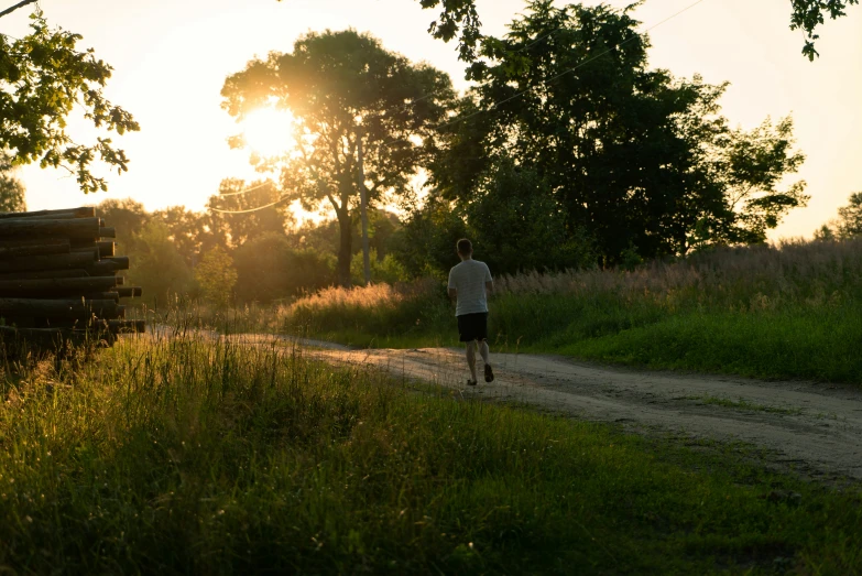 the man walks down a path while the sun goes down