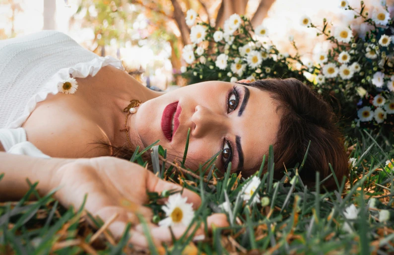 a woman laying down in the grass with flowers