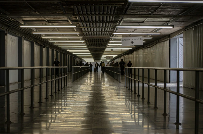 people in a hallway with long metal fences