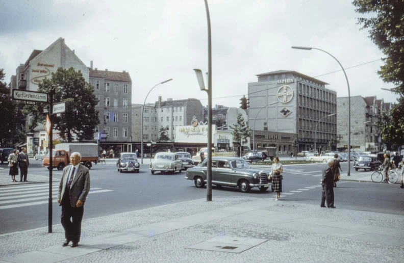 a city street has cars and people waiting to cross