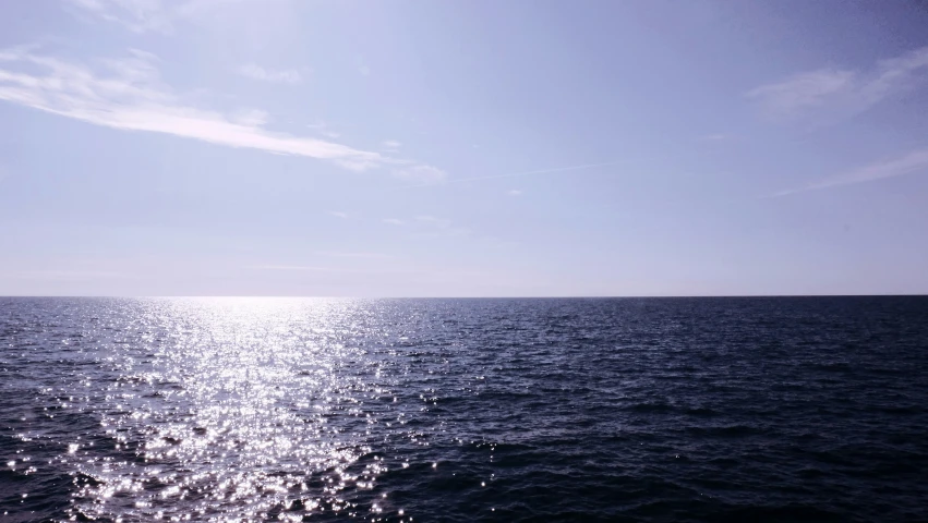 the ocean with blue sky and sunshine reflecting off of it