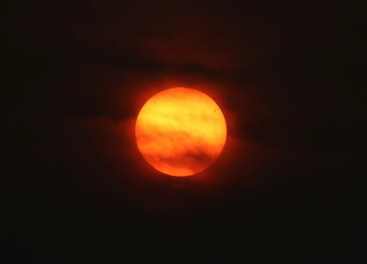 a large red sun is shining through the dark cloud