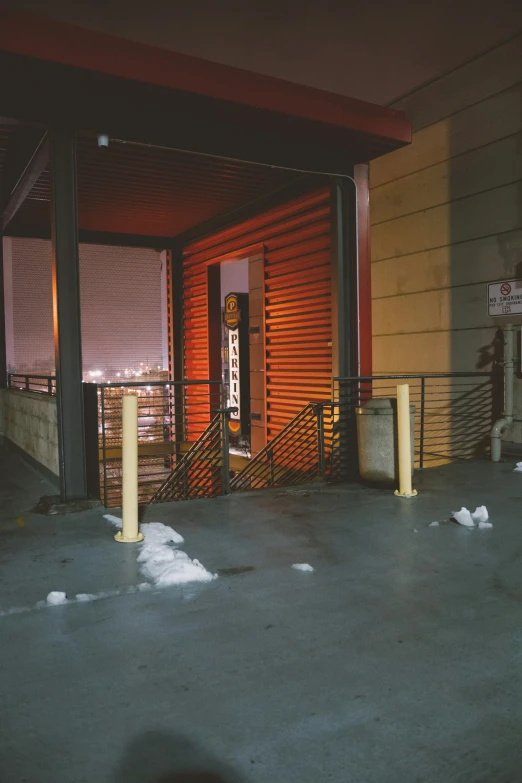 the corner of a sidewalk with snow and a doorway at night
