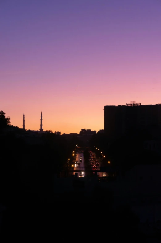 a street sign at sunset over a road with buildings in the background