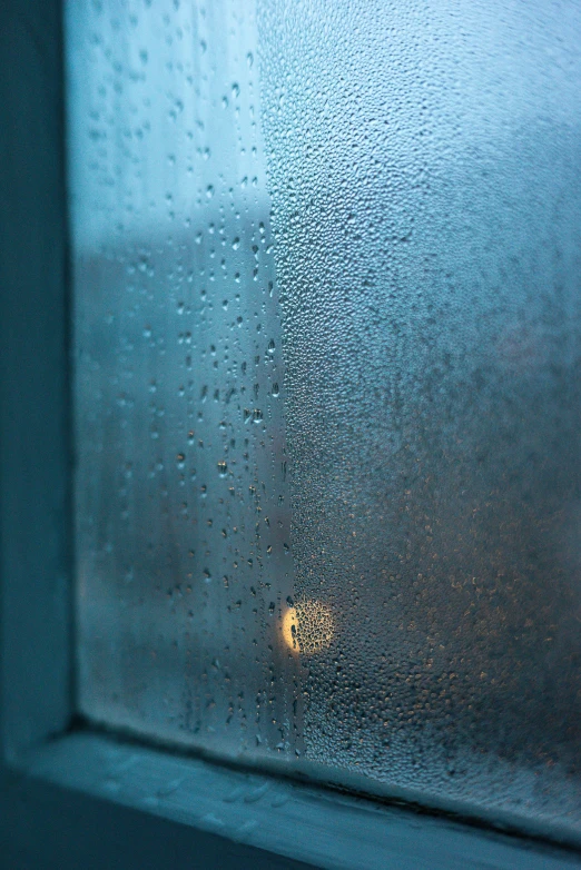 a window with rain drops and a street light in the background