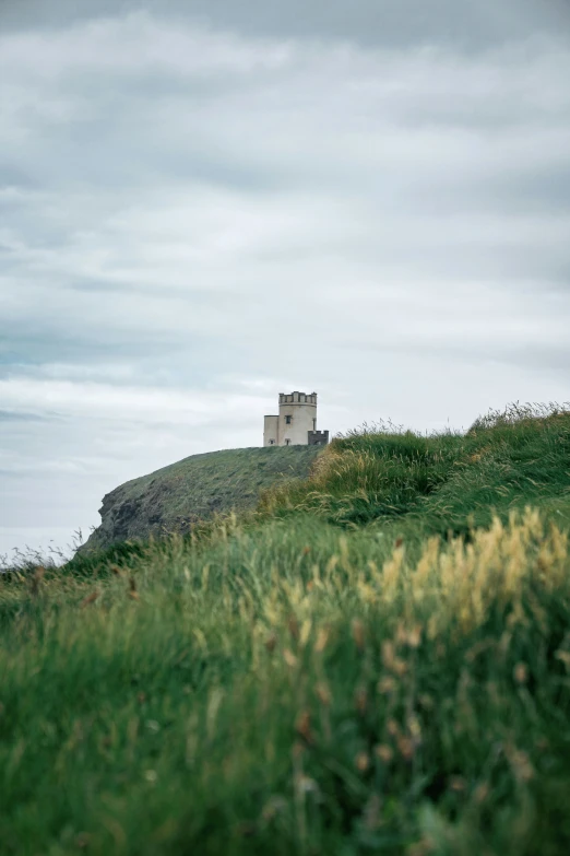 a building sitting on top of a green hillside next to the ocean