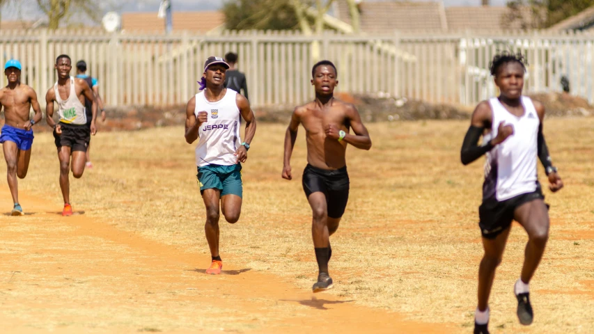 a group of men running across a dirt field