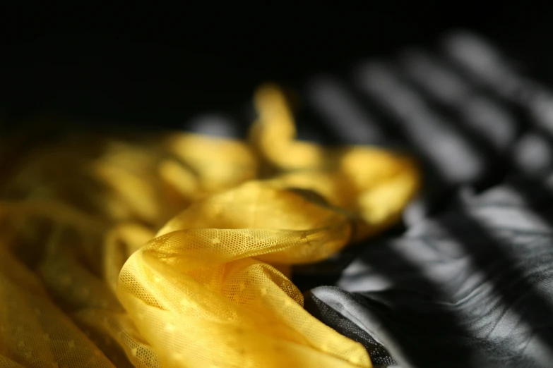 a yellow silk neck tie sitting on top of a black fabric