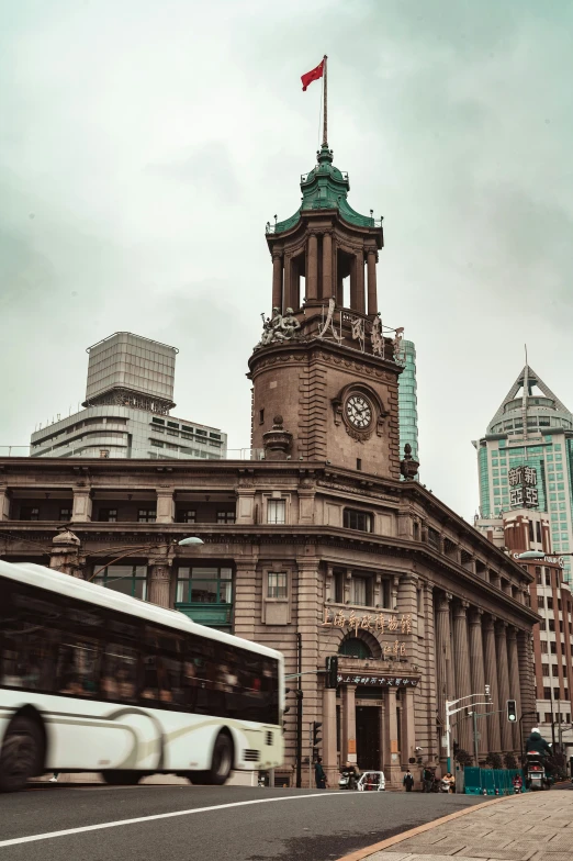 a bus drives past a building with a clock tower