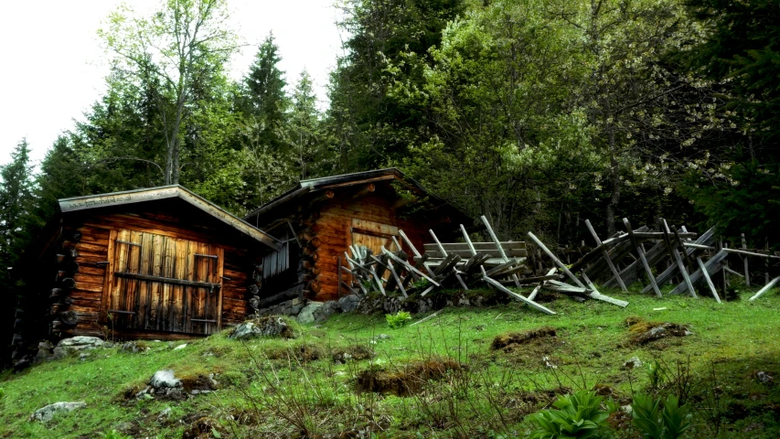 two wooden huts sitting next to each other in the grass