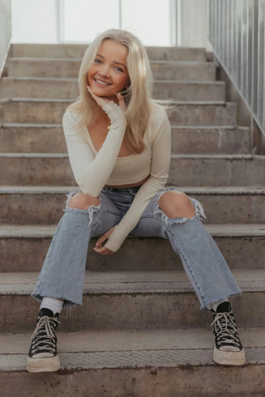 a young woman wearing jeans sitting on the steps