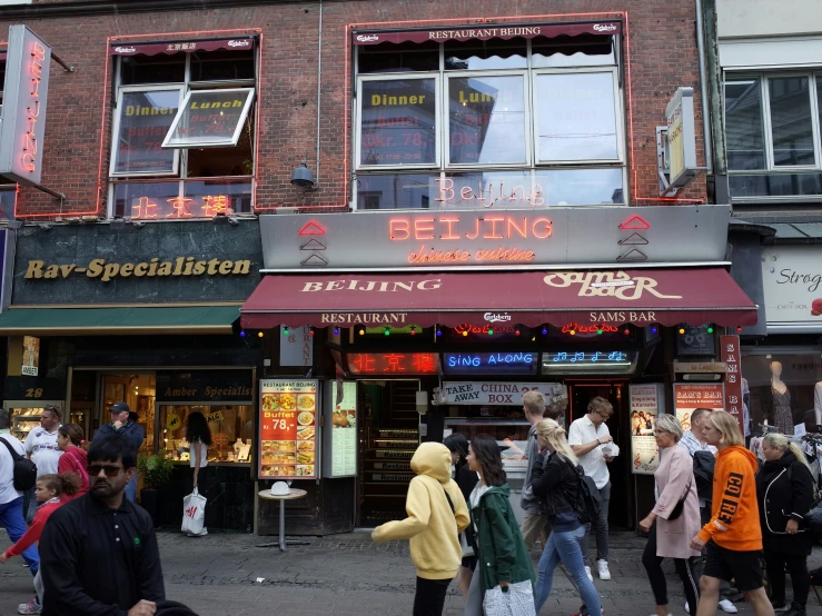 several people walk down the street near many stores