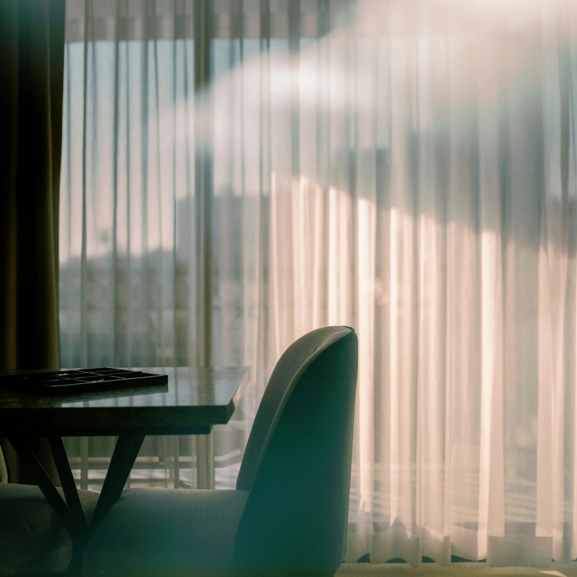 a dining table and chairs in front of sheer curtains