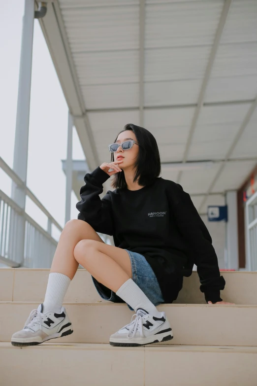 a girl wearing silver and black is sitting on stairs with her head up