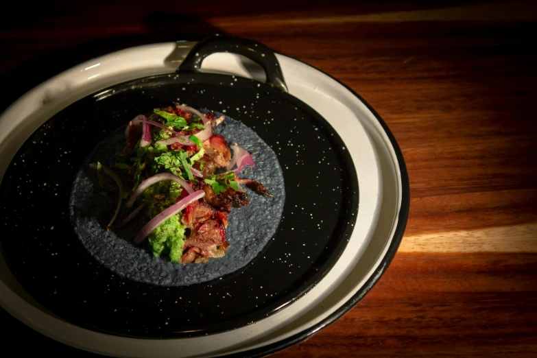 a black plate topped with a salad and onions