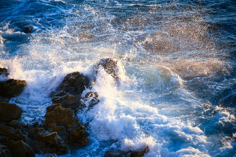 a large wave hitting on rocks near the ocean