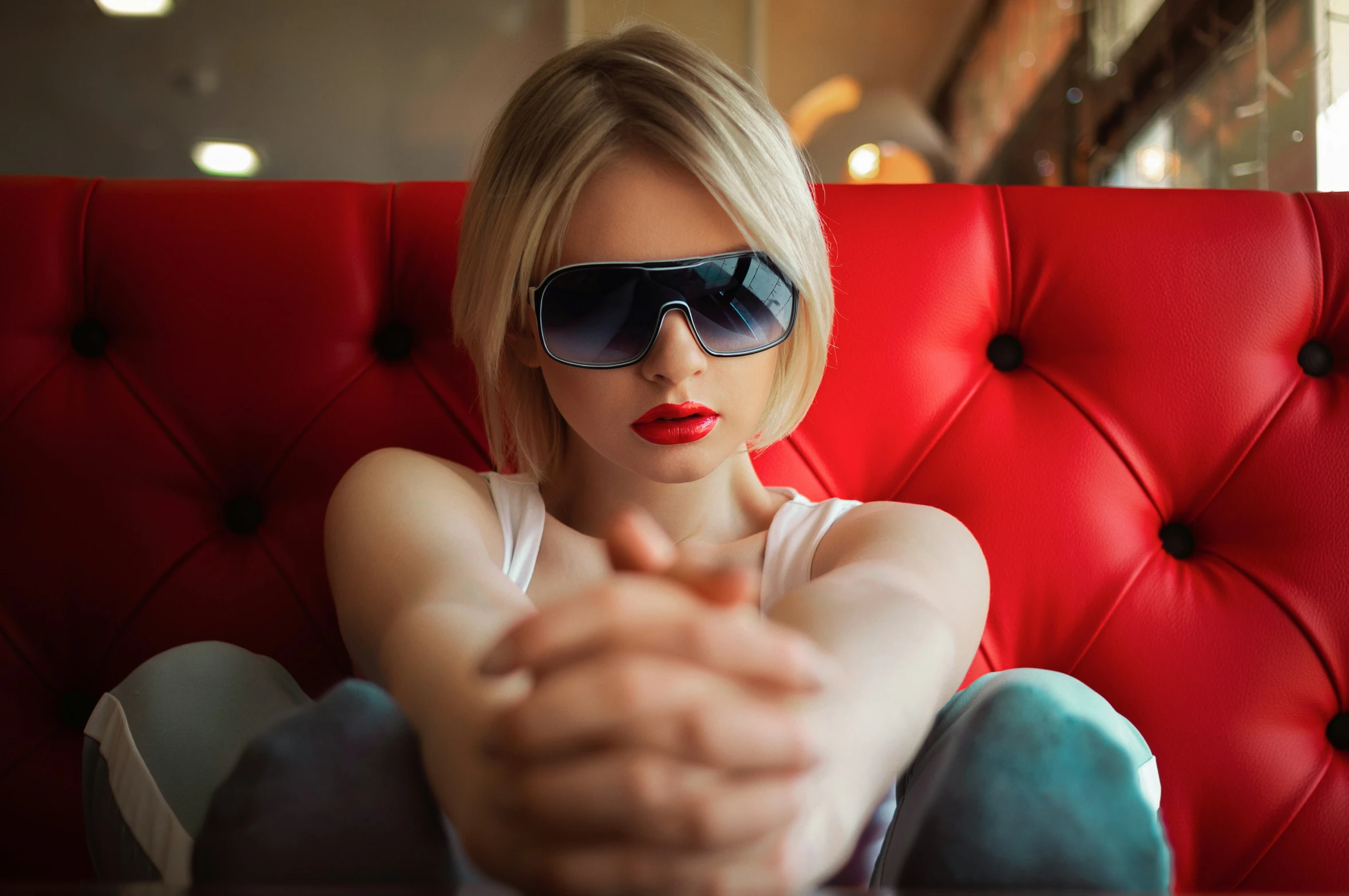 a beautiful woman wearing sunglasses sitting on a red chair