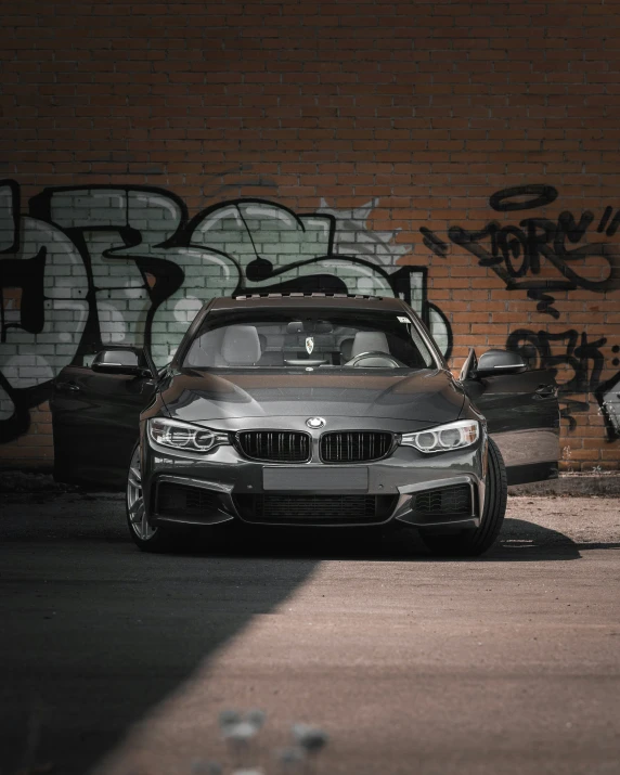 a grey bmw car is parked next to graffiti