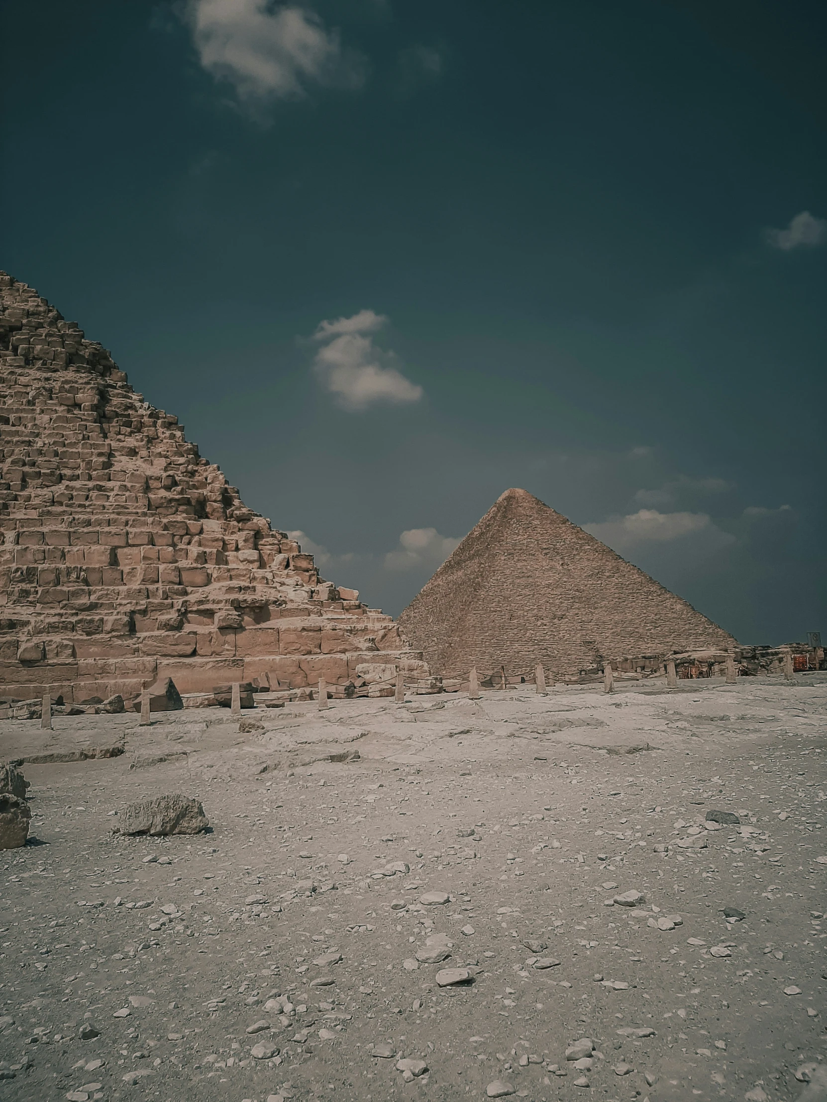 three stone pyramids in the desert with some blue sky in the background