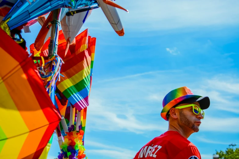 a man standing underneath a rainbow colored kite