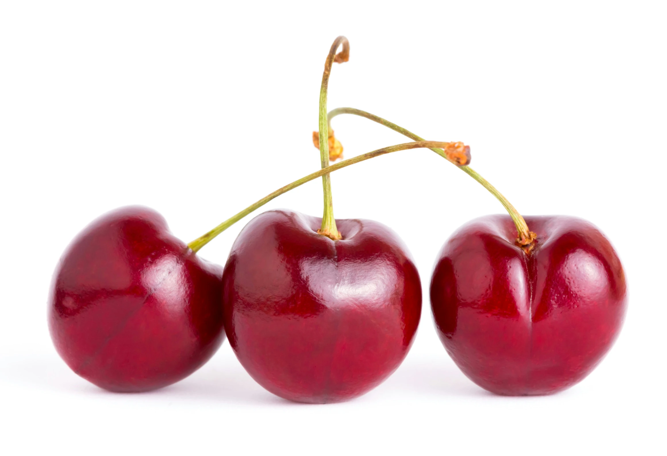 three cherry fruits sit atop one another on a white surface