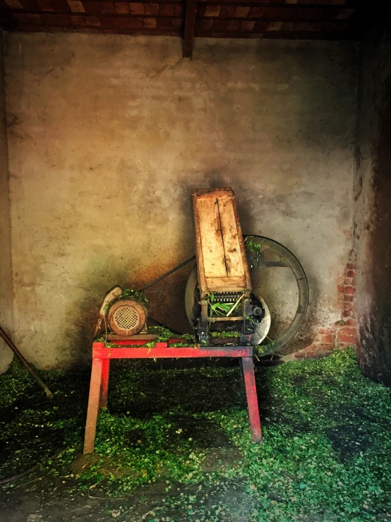 an old machine and some grass in an indoor barn