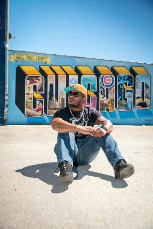 a man sitting in front of a wall with graffiti