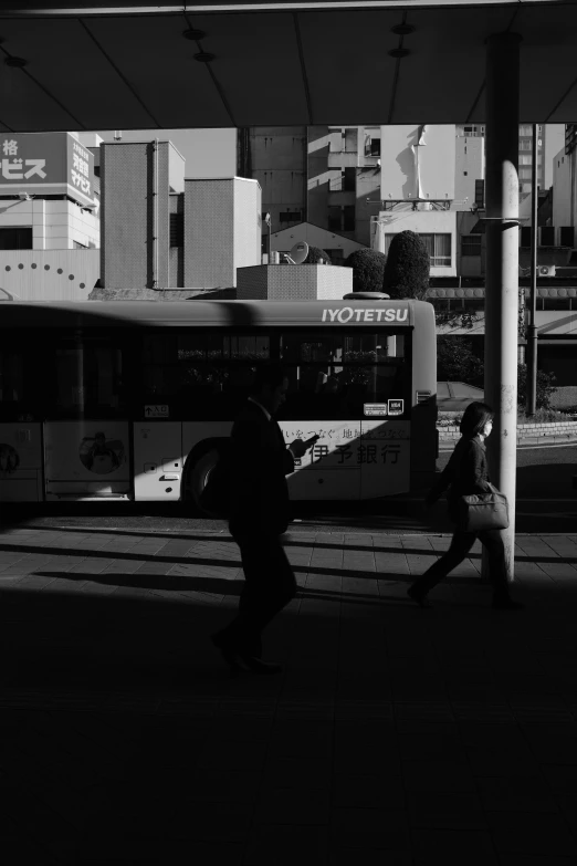 a couple of people walking down a street near a bus