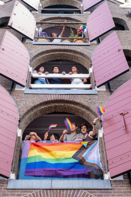 an image of a rainbow flag being held on a balcony