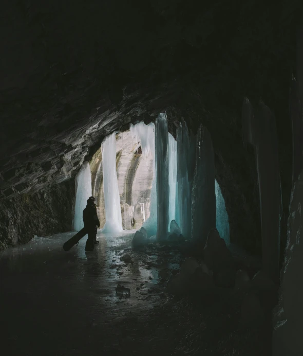 a man is standing in a cave by the water