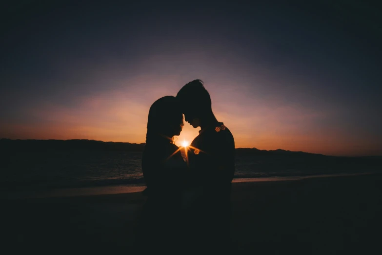 a couple is silhouetted against the sun on a beach